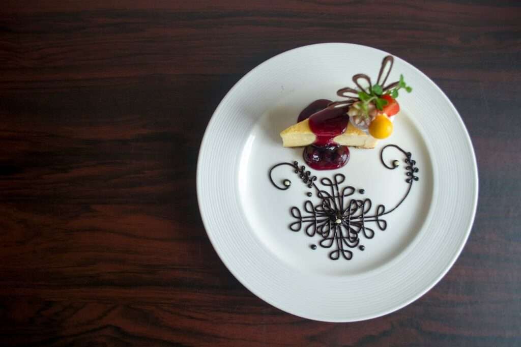 Exquisite plated dessert with artistic chocolate design and fruit garnish on a white plate.