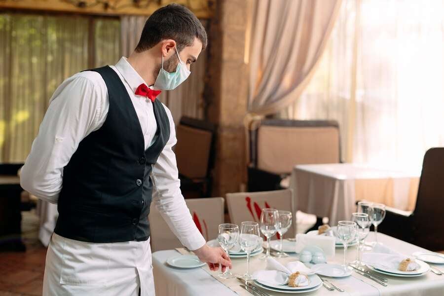 waiter-wearing-medical-protective-mask-serves-table-restaurant_109285-7874