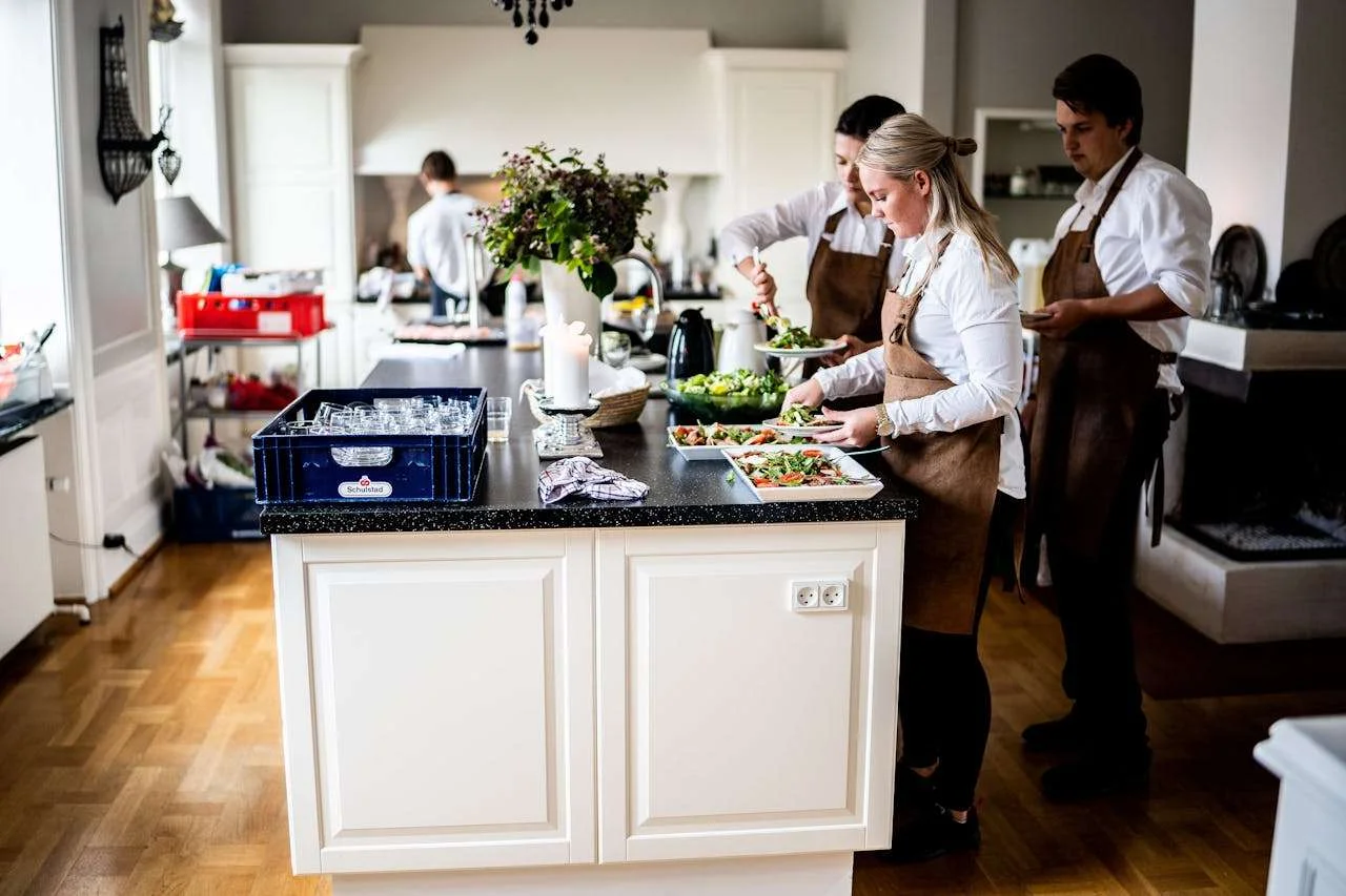 Chefs in a modern kitchen preparing dishes with precision and teamwork, highlighting culinary expertise and professionalism.